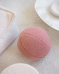 Guava pink teddy bal kinder sierkussen van Wigiwama op een licht tapijt. Gemaakt van OEKO-TEX® teddystof en perfect voor spelen, decoreren of relaxen.