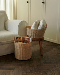 Sfeerbeeld van de 2 rotan manden in een woonkamer, op een bijzettafeltje en naast de bank