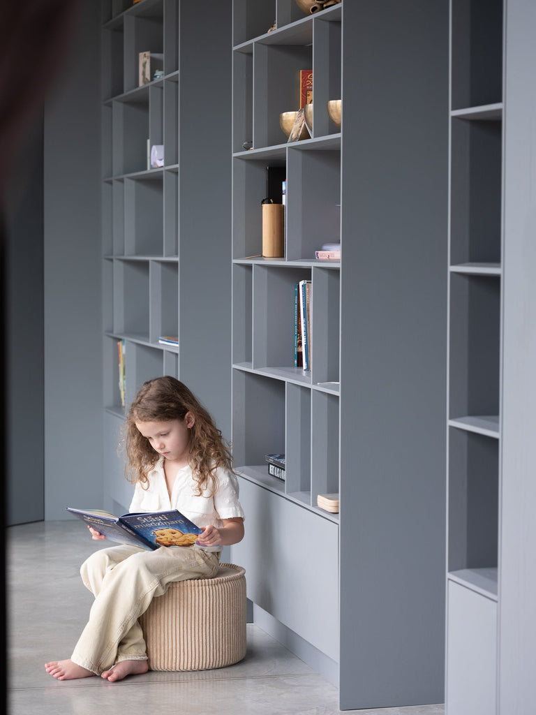 Meisje wat een boekje zit te lezen op een beige ribstof kinder poef van Wigiwama